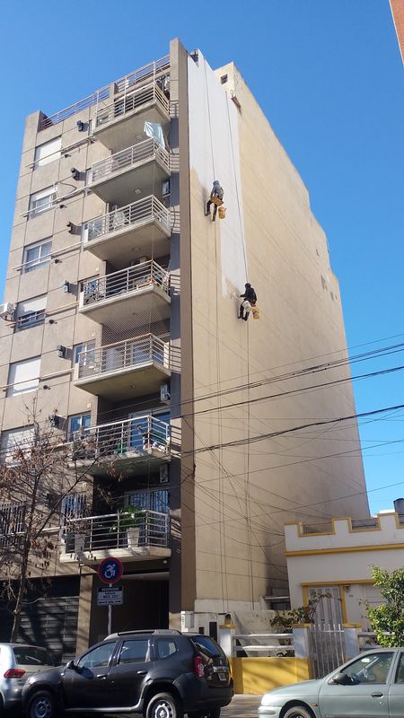 Técnicos en acceso por cuerdas impermeabilizando la medianera de un edificio en Monte Castro