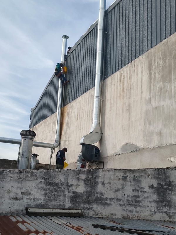 Técnicos montando un ducto de extracción de acero sobre muro exterior en altura