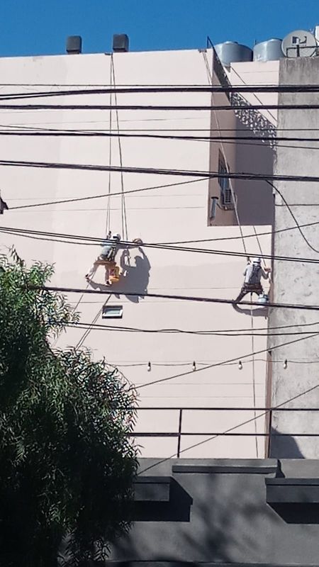 Dos técnicos en acceso por cuerdas pintando una medianera